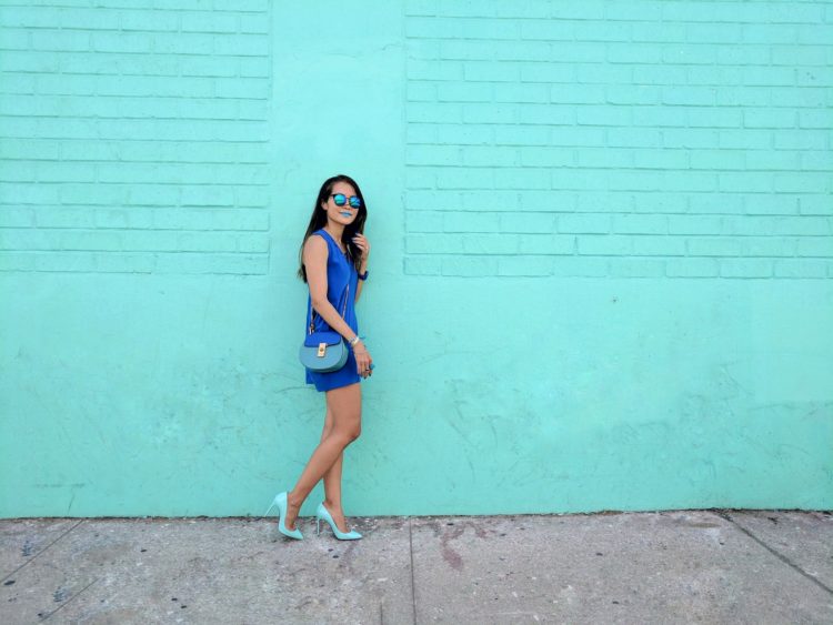 girl in blue standing in front of teal wall